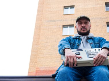 Parktaki bir hip hop dayakçısı 90 'ların davul makinesini elinde tutuyor. Hip Hop Yapımcıları ve Beatmakers için Retro Dijital Müzik Enstrümanı