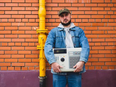 90 'lı yılların davul makinesi bir dayatıcının elinde tuğla duvara karşı. Hip Hop Yapımcıları ve Beatmakers için Retro Dijital Müzik Enstrümanı