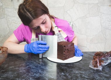 Pasta şefi kız ganache sürülmüş çikolatalı kek yapıyor.