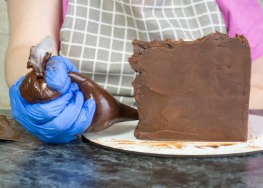 Pasta şefi kız ganache sürülmüş çikolatalı kek yapıyor.