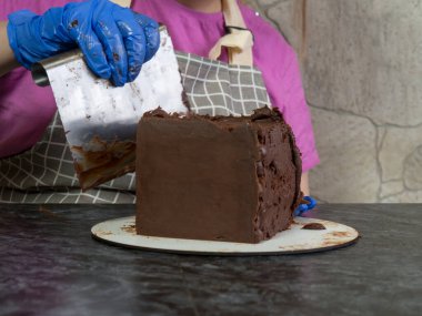 Pasta şefi kız ganache sürülmüş çikolatalı kek yapıyor.