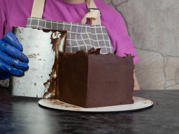 pastry chef girl makes chocolate cake smeared with ganache