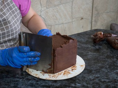 Pasta şefi kız ganache sürülmüş çikolatalı kek yapıyor.