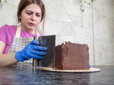 Pasta şefi kız ganache sürülmüş çikolatalı kek yapıyor.