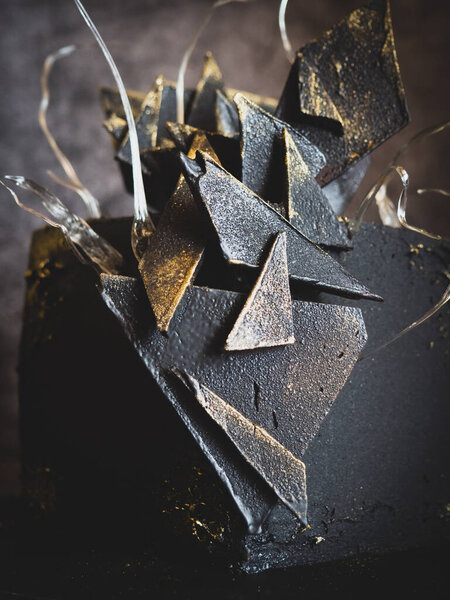modern black square chocolate cake covered with velour and decorated with isomalt and chocolate bar
