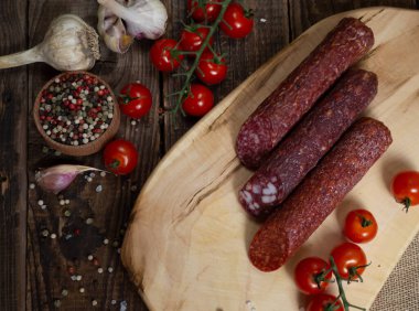 Tahtadaki farklı salam türleri baharatlar ve vişneli domateslerle