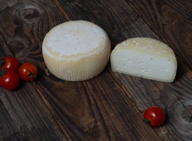 Peynir çarkı ve peynir parçaları ahşap bir masada.