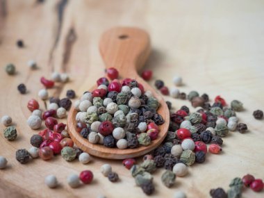 Biberi tahta kaşıkla karıştır. Ahşap bir arka planda siyah, kırmızı, beyaz ve yeşil bezelyeler. Yakın plan.