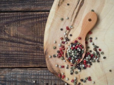 Biberi tahta kaşıkla karıştır. Ahşap bir arka planda siyah, kırmızı, beyaz ve yeşil bezelyeler. Yakın plan.