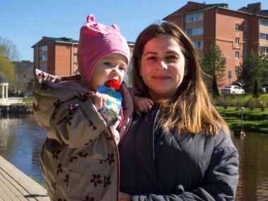 Güneşli bir günde parkta yürüyen mutlu bir anne ve kız çocuğu.