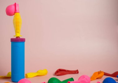 Pembe balonun yanında plastik el pompası. Tatile hazırlanıyorum. Doğum günü partisi organizasyonu. Pembe arkaplanda dekoratör aracı