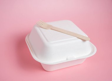 Beyaz kağıt yemek kabı ve pembe zemin üzerinde ahşap çatal, kopyalama alanı