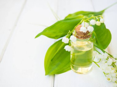 Vadi Zambağı, Convallaria majalis esaslı yağ (özet, tentür, infüzyon, çare) tahtadan bir arka planda taze Convallaria çiçekleri ve metin için alan