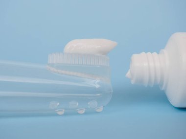 Çocukların silikon diş fırçası ve yapıştırıcısı mavi arka planda yakın plan, diş fırçası parmağında.