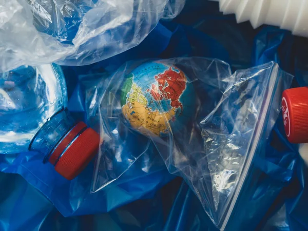 a globe in a plastic bag in a pile of plastic waste