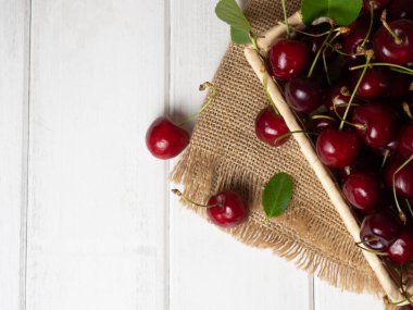 fresh cherries in a wicker basket on a white wooden table