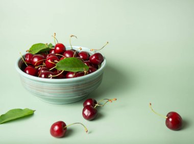 ripe cherries in a bowl on a menthol background with place for your text