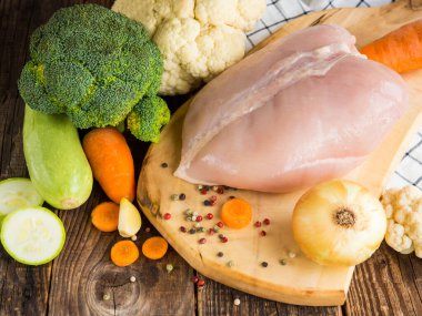 fresh chicken breast and vegetables on rustic wooden background