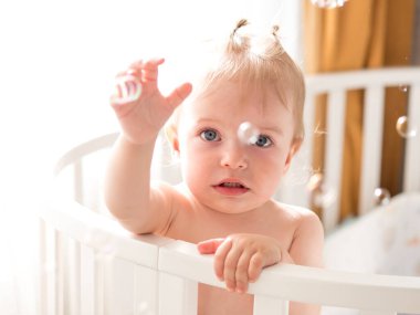 one-year-old child cheerfully plays with soap bubbles