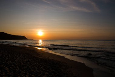 Denizde güzel bir gün batımı. Gün batımında plaj ve sörf.