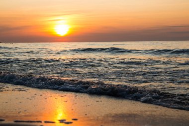 Denizde güzel bir gün batımı. Gün batımında plaj ve sörf.