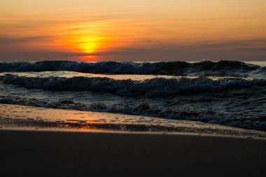 Denizde güzel bir gün batımı. Gün batımında plaj ve sörf.