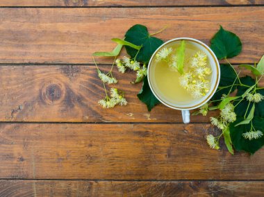 Bir fincan yeşil çay ve ahşap arka planda ıhlamur, işe yarar ıhlamur çiçekleri halk hekimliği konsepti