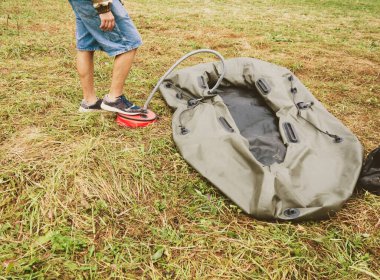 Bir adam lastik bir tekneyi pompayla şişirir.