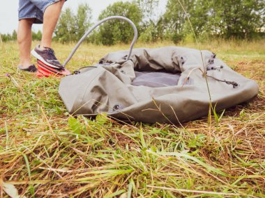 Bir adam lastik bir tekneyi pompayla şişirir.