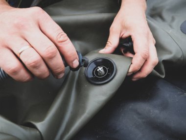 Bir adam lastik bir tekneyi pompayla şişirir.