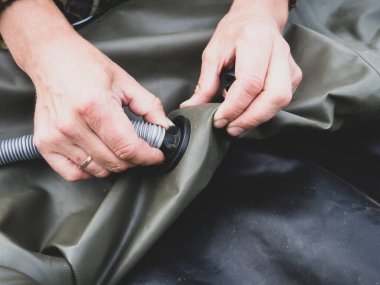 Bir adam lastik bir tekneyi pompayla şişirir.