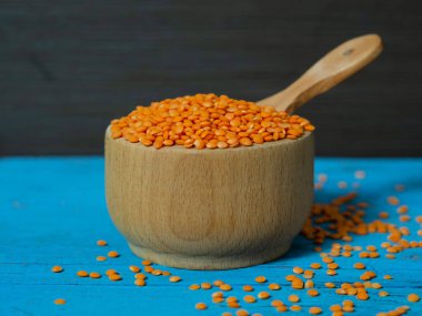 Tahta bir tabakta kırmızı mercimek ve eski bir kırsal masada kaşık. Vejetaryen yemeği..