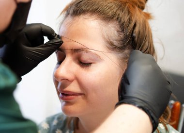 Makyöz, profesyonel bir yüz bakımıyla kaşlarını yoluyor..