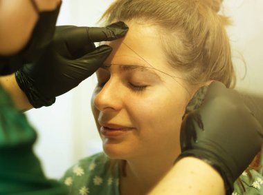 Makyöz, profesyonel bir yüz bakımıyla kaşlarını yoluyor..