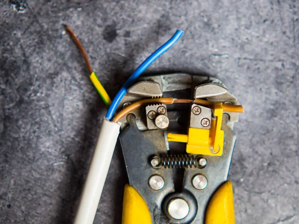 An electrician strips electrical wires with a stripper.