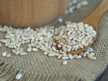 Tahta bir kaşıkta çiğ inci arpası Eski bir ahşap masaya dökülüyor