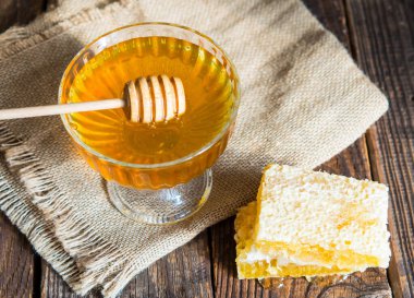 Bal damlaları bal kabından güzel bir cam kaseye damlıyor. Yakın plan. Sağlıklı organik, kalın bal ve tarak.