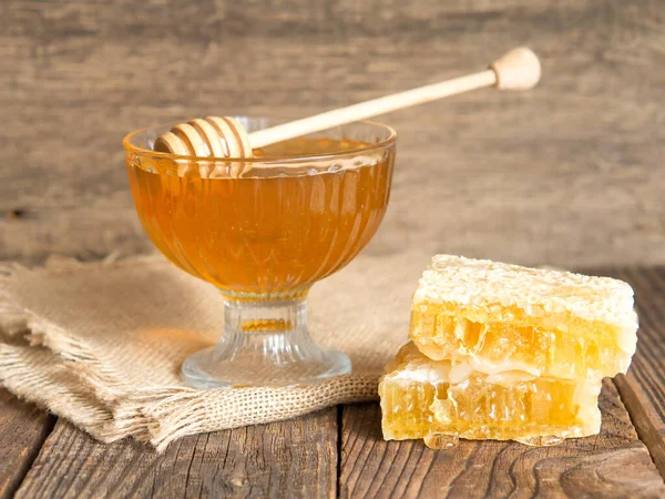 Honey drips from a honey dipper into a beautiful glass bowl. Close-up. Healthy organic thick honey and combs.