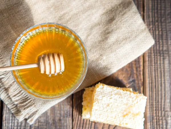 Honey drips from a honey dipper into a beautiful glass bowl. Close-up. Healthy organic thick honey and combs.