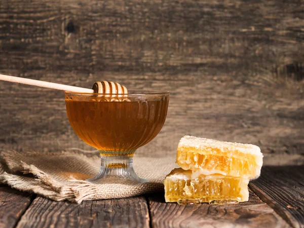 Honey drips from a honey dipper into a beautiful glass bowl. Close-up. Healthy organic thick honey and combs.