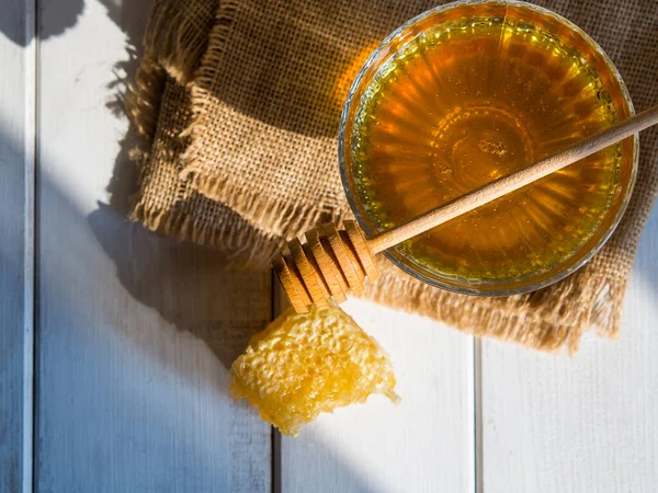 Honey drips from a honey dipper into a beautiful glass bowl. Close-up. Healthy organic thick honey and combs.