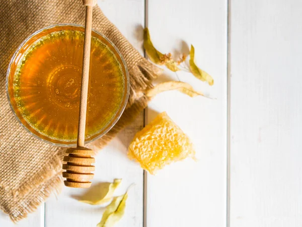 Honey drips from a honey dipper into a beautiful glass bowl. Close-up. Healthy organic thick honey and combs.