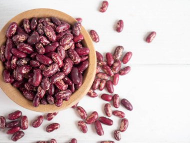 Tahta bir kasedeki kırmızı fasulyeler beyaz tahta bir masanın üzerinde, boşluğu kopyala