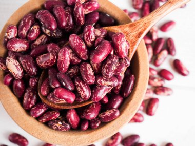 Tahta bir kasedeki kırmızı fasulyeler beyaz tahta bir masanın üzerinde, boşluğu kopyala