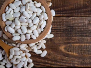 Tahta bir kasedeki beyaz fasulyeler eski bir masa üzerinde, baklagiller, kopyalama alanı