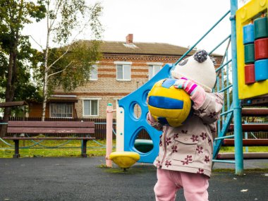 Küçük çocuk bir sonbahar günü oyun bahçesinde topla oynuyor.