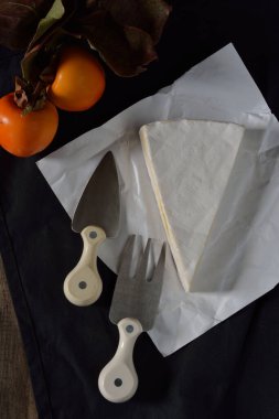 Peynirli peynir, çatal, peynir bıçağı ve hurma yanında da meyve.