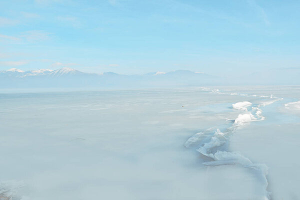 Зимние участки замёрзшего озера и горный покров со снегом 