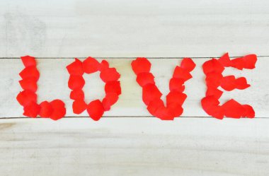 Aşk kelimesi kırmızı gül yapraklarıyla yazılmış.