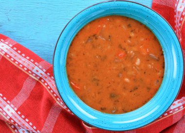 Kırmızı mutfak havlusu ve turkuaz masa üzerinde beyaz fasulye çorbası.